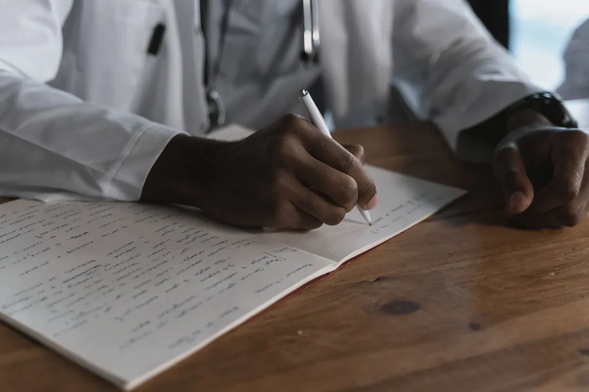 Doctor writing notes, illustrating health plan costs and deductibles