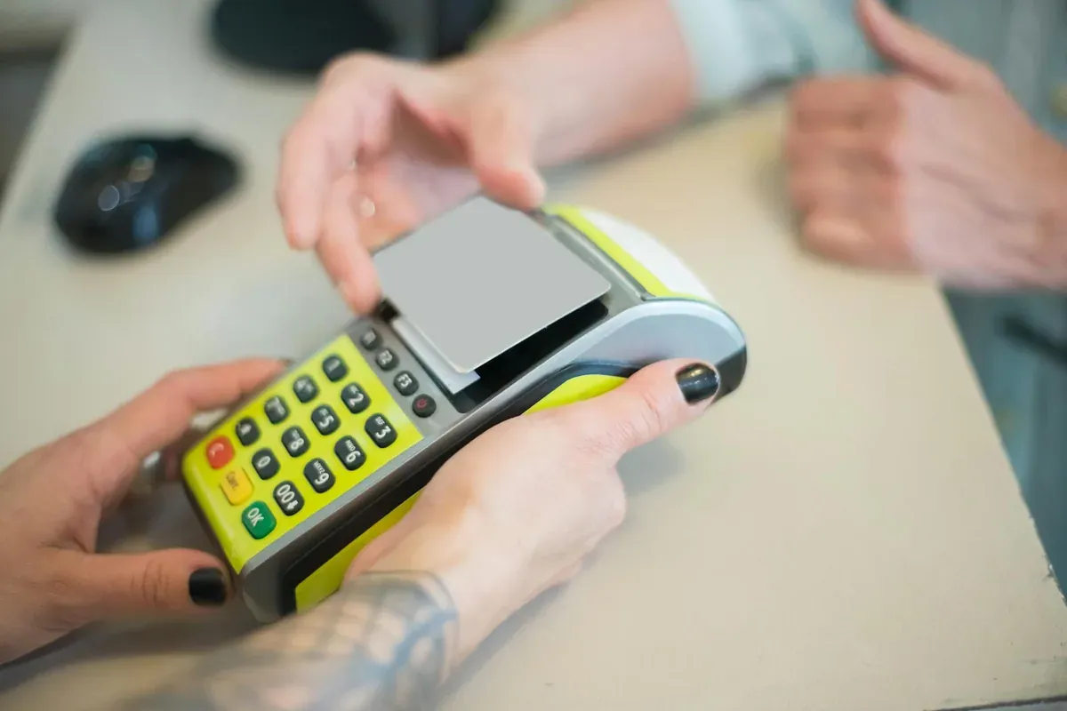 A woman scanning her card at a coffee shop counter — cash versus card spending psychology