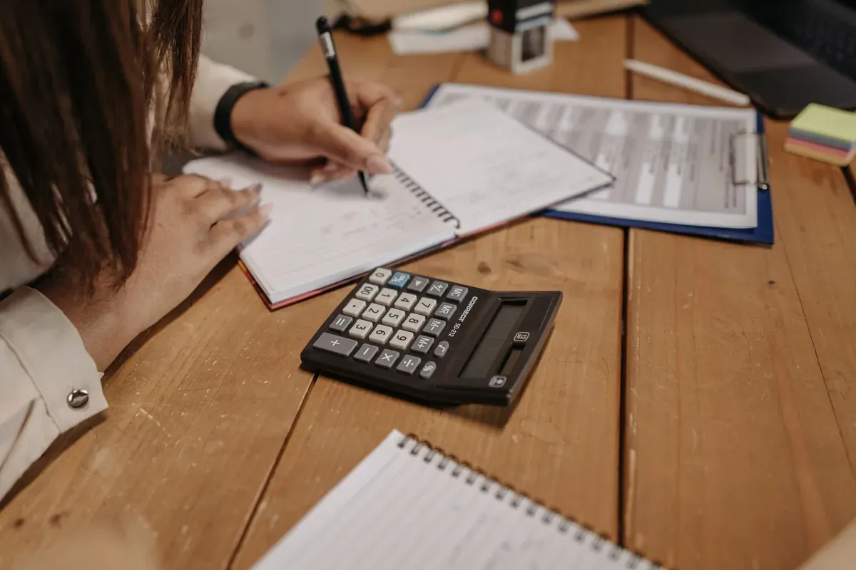 A woman reviewing financial planning documents at a desk, comparing savings options for 2026