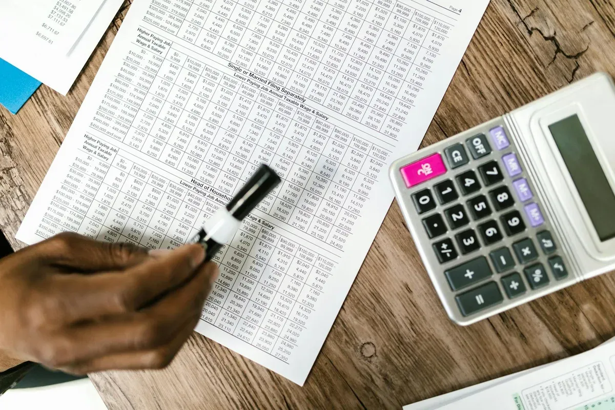 A calculator and financial paperwork laid out on a desk, representing the process of calculating credit card debt payoff timelines