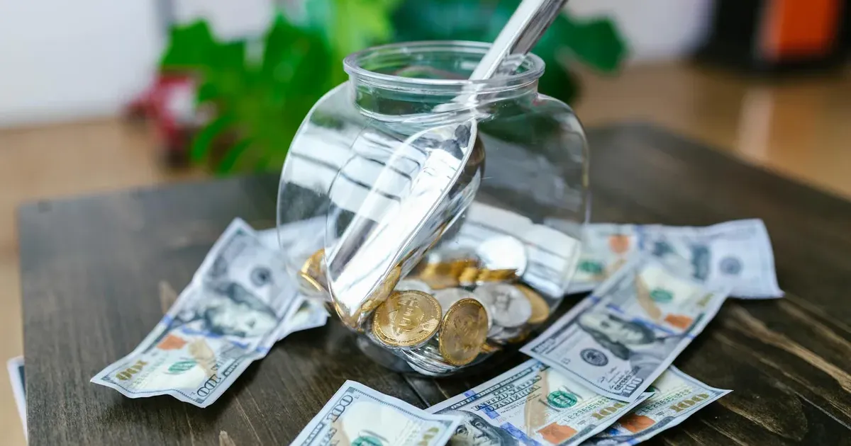 Glass jar filled with dollar bills representing an emergency fund savings goal