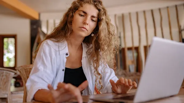 Γυναίκα με laptop σε καφέ διαβάζει finfluencers συμβουλές για χρήματα στα social media