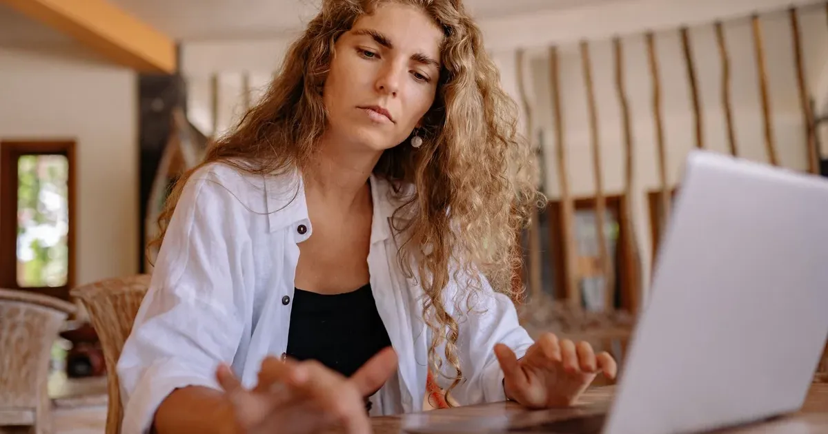 Γυναίκα με laptop σε καφέ διαβάζει finfluencers συμβουλές για χρήματα στα social media