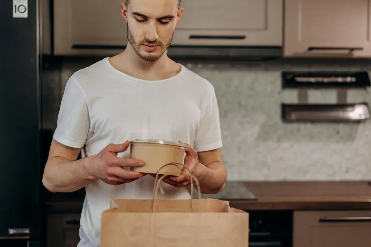 Man holding meal prep containers, illustrating how planned grocery shopping saves money in 2026