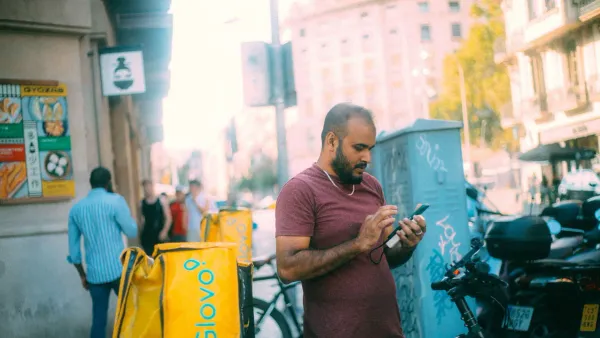 Man checking his phone on a city street while reviewing hidden bank fees on his checking account