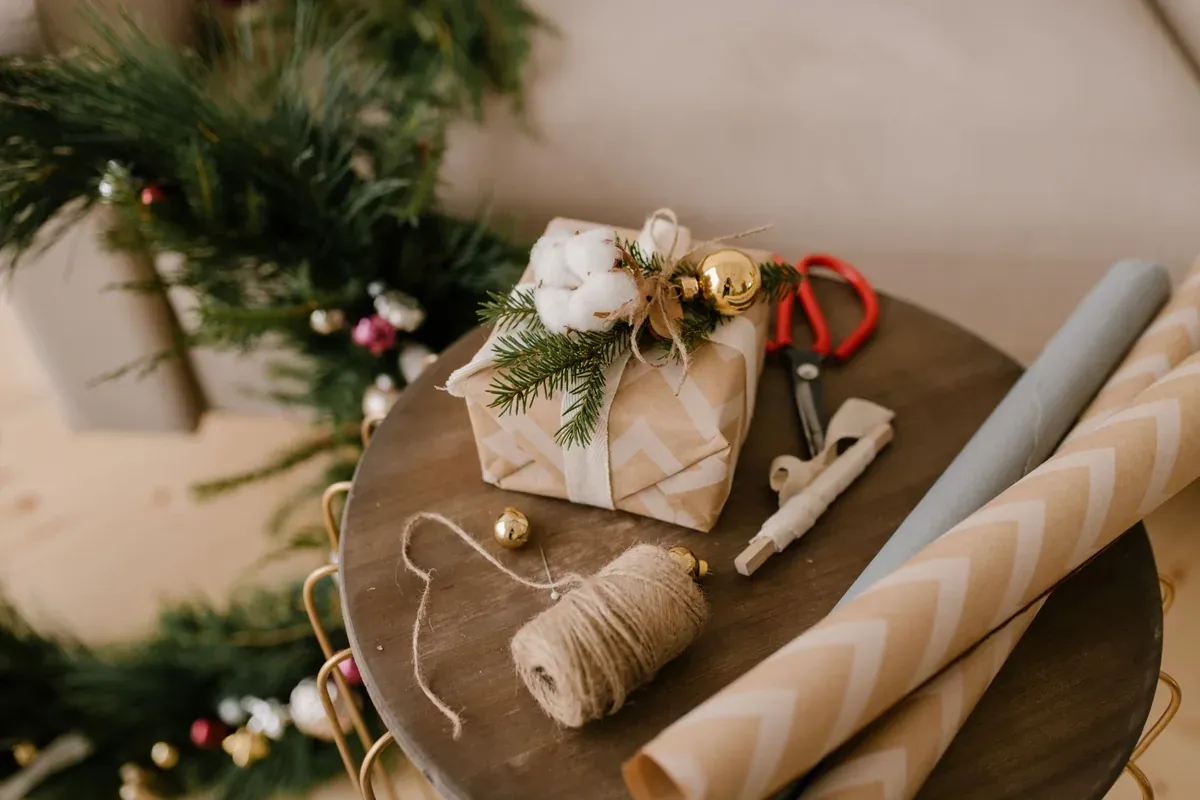 Wrapping holiday gifts on a table while checking a gift budget list
