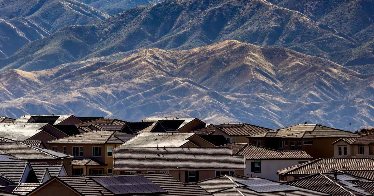 Aerial view of a suburban American neighborhood with dry mountains behind it, representing rising home insurance costs in 2026