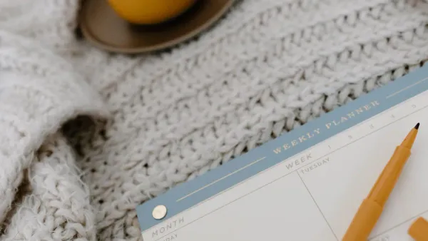 Desk with a planner and calendar used to plan 2027 HSA and FSA open enrollment contributions