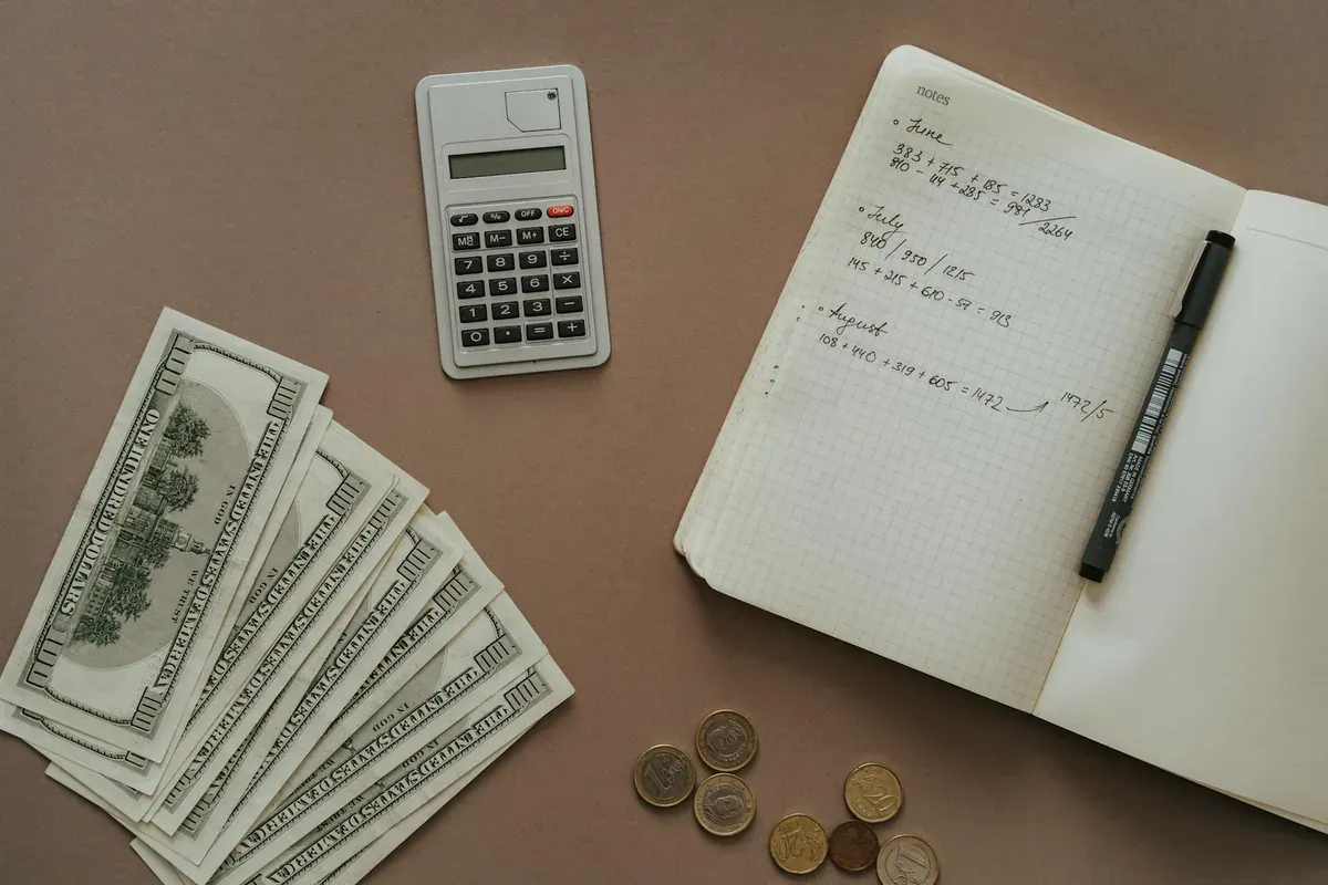 Notebook open to budget planning page with pen and cash on wooden table