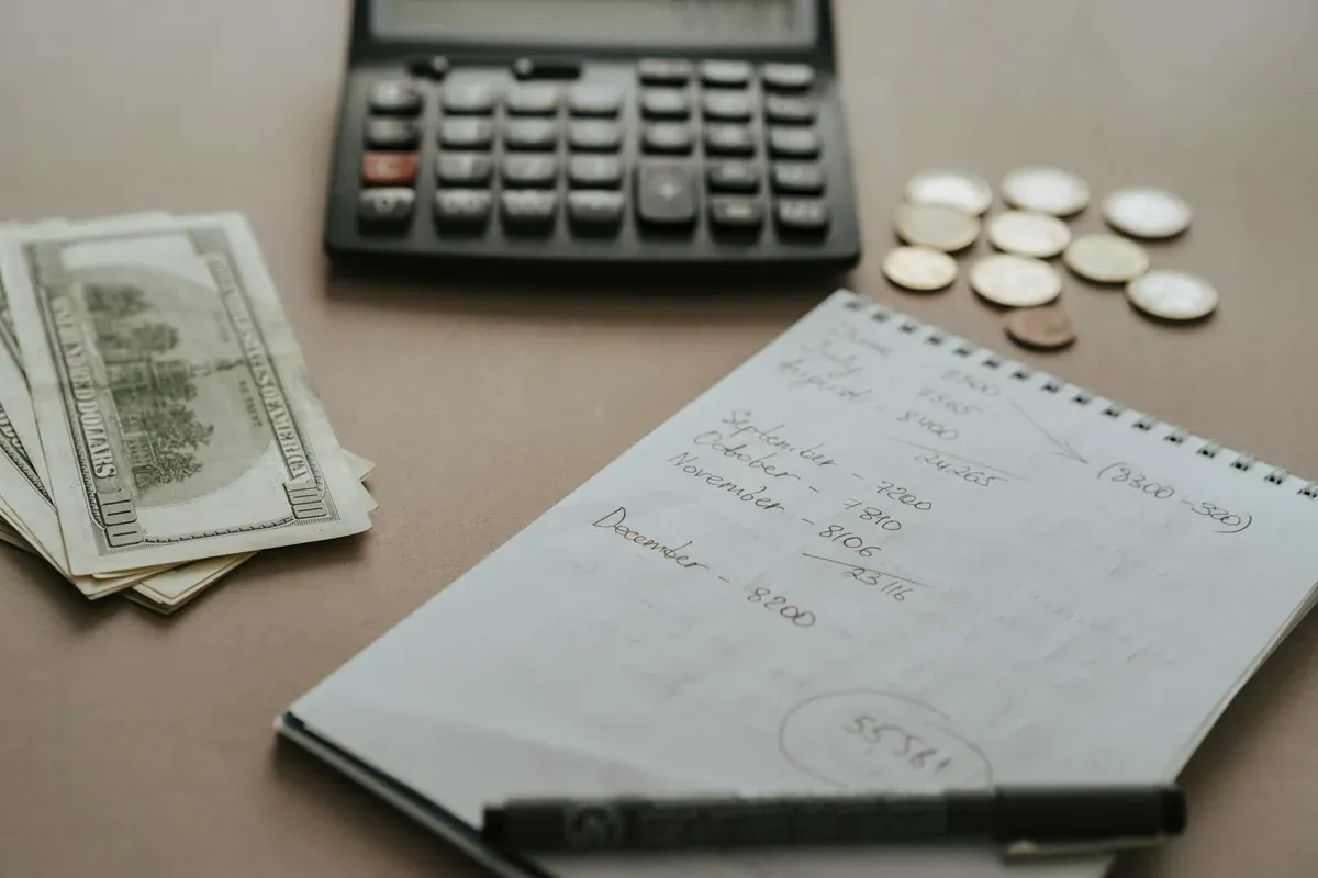 Σημειωματάριο με budget διακοπών και πέννα δίπλα σε καφέ — οργάνωση οικονομικών για καλοκαιρινές διακοπές