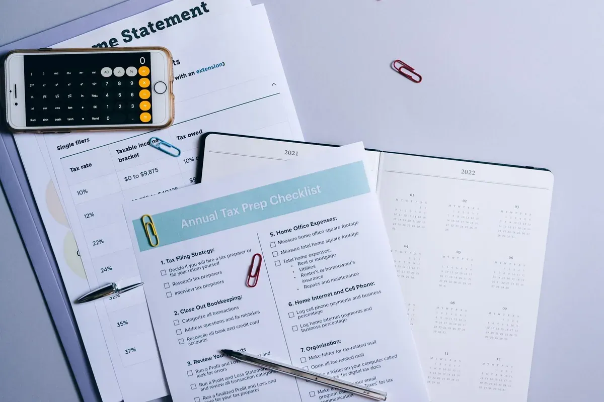 Documents and a mobile phone showing budget tracking on a desk
