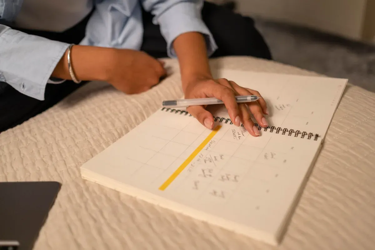A person writing in a notebook with a pen — intentional journaling for a no-buy challenge