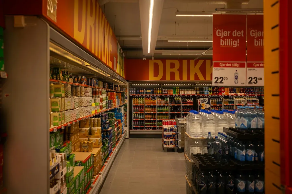 Ράφια σούπερ μάρκετ με ποτά και προϊόντα, αντιπροσωπεύοντας τις αυξήσεις τιμών και τον πληθωρισμό στο καλάθι του νοικοκυριού