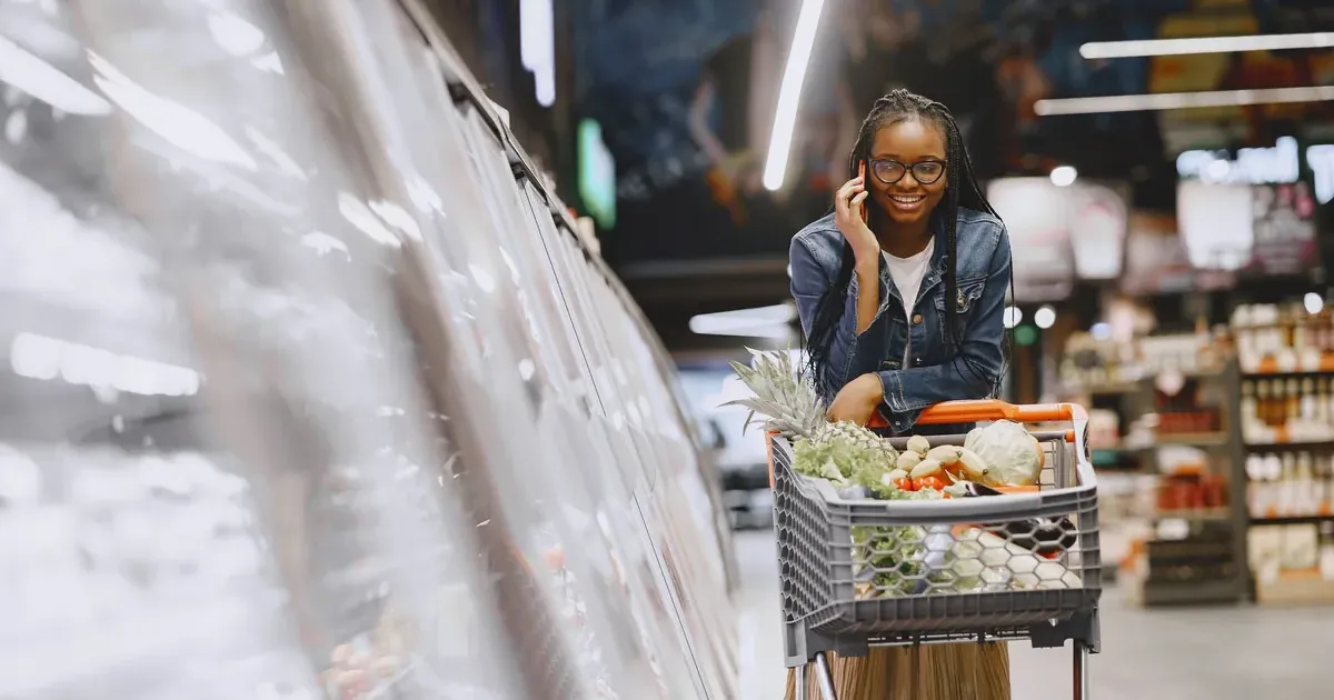 Woman shopping in a grocery store aisle, illustrating rising US grocery costs against wage growth in 2026