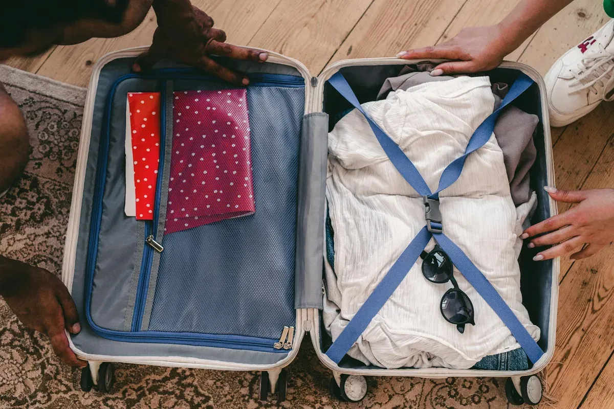Open suitcase with clothes and sunglasses being packed for summer vacation travel