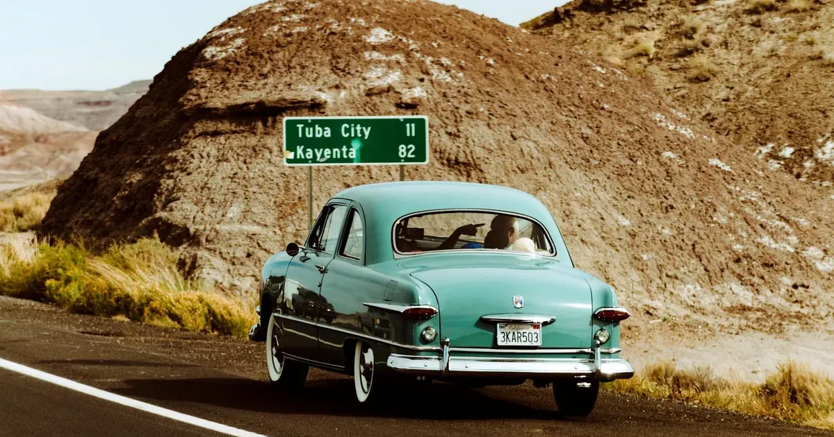 Vintage car on a summer road trip highway — summer travel budget 2026 planning