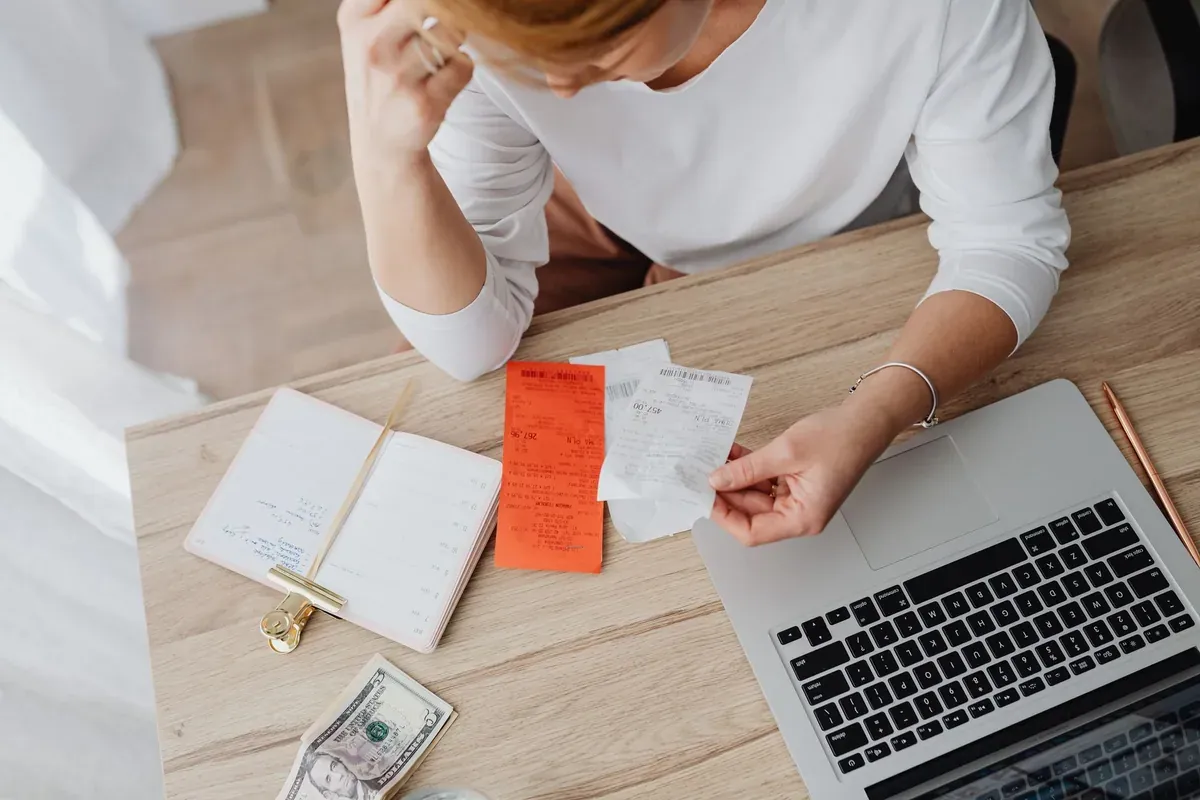 Woman reviewing receipts at a desk, comparing grocery spending month by month