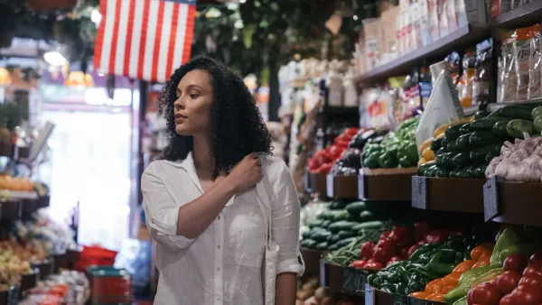 Woman shopping in a fresh produce market aisle — tracking grocery budget against 2026 tariffs
