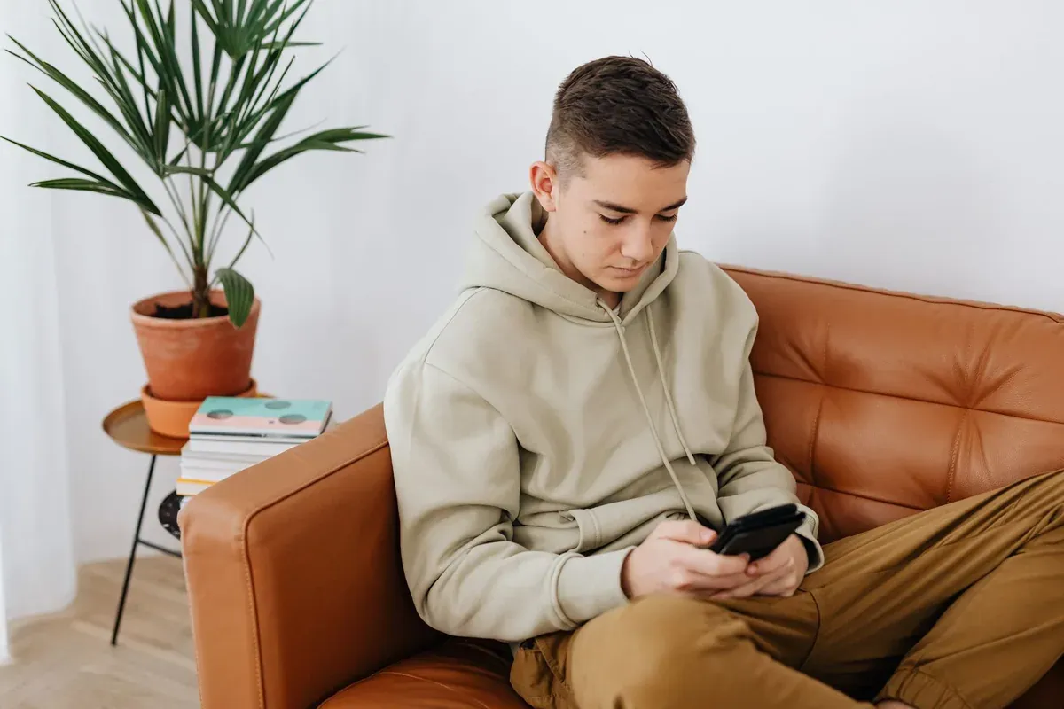 A teenager checking a banking app on their phone at home, part of learning digital money management