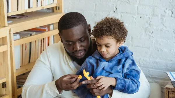 A father and young son sitting together at home, part of teaching kids about money and financial literacy