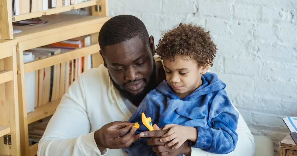 A father and young son sitting together at home, part of teaching kids about money and financial literacy