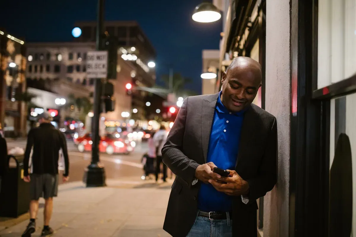 Man checking his smartphone on a city street at night