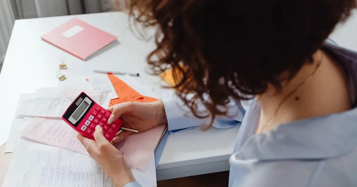 Woman using a calculator to track net worth without linking bank accounts