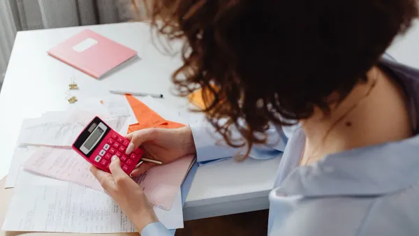 Woman using a calculator to track net worth without linking bank accounts